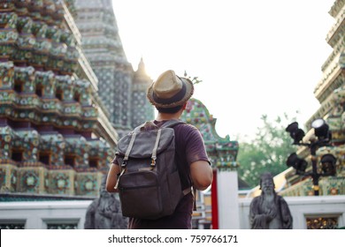 Young Asian traveling backpacker in Wat Pho with India inspired temple in Bangkok, Thailand