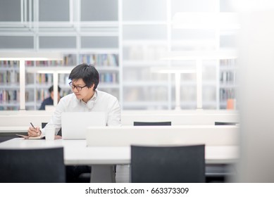 Young Asian University Student Working With Laptop Computer And Notebook In Library, Self Learning And College Lifestyle Concepts
