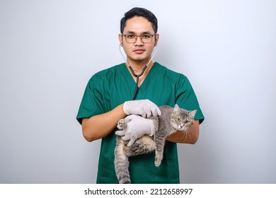 Young Asian Vet Wearing Scrubs And Glasses Examine Pet Cat Isolated Over White Background