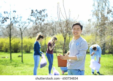 Young Asian Volunteer With Team Outdoors