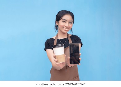 A young asian waitress or barista suggests to order coffee via a delivery app or company website. Online delivery app concept. Isolated on a light blue background.