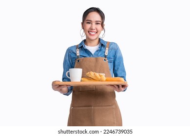 young asian waitress barista wearing apron hand hold bread and coffee drink on wooden tray smiling warm welcome invite customer to her coffee shop studio shot on white background - Shutterstock ID 2246739035