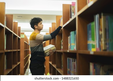 Young Asian Is Walking Between Book Shelf,choose Books In The Library,Concept Educational.