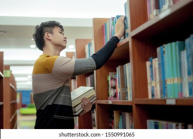 Young Asian Is Walking Between Book Shelf,choose Books In The Library,Concept Educational.