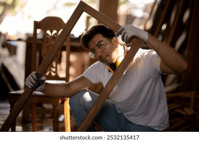 Young Asian White Carpenter man sitingholding square of work peice, finishing product looking at camera.