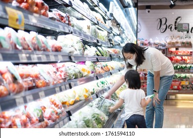 Young Asian Woman And 2 Year Old Kid With Face Mask In Supermarket. Concept For Life In Outbreak And New Normal.