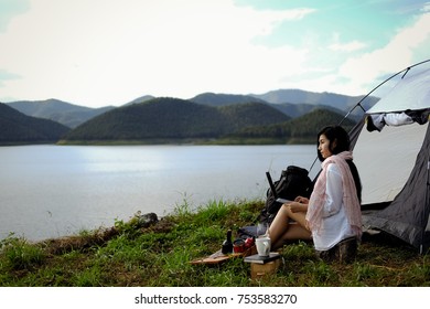 Young Asian Woman Active Camping And Using Laptop In Stunning Mountain Wilderness Near The Lake.