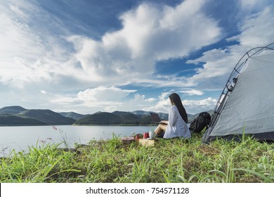 Young Asian Woman Active Camping And Using Laptop In Stunning Mountain Wilderness Near The Lake.