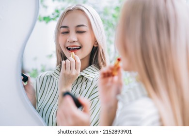 Young Asian woman applying lipstick in front of mirror
 - Shutterstock ID 2152893901