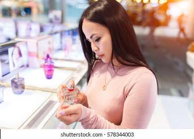 Young Asian Woman Applying Perfume On Her Wrist In Duty Free Store.