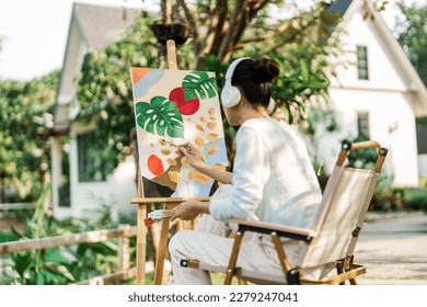 Young asian woman artist painting on canvas.Female artist drawing with inspiration in garden