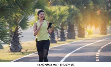 A young Asian woman athlete runner jogging in city stadium in the sunny morning to keep fitness and healthy lifestyle. Active healthy runner jogging outdoor. Sports and recreation