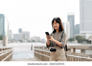 Young Asian woman backpack traveler using mobile phone in express boat pier on Chao Phraya River in Bangkok. Journey trip lifestyle, world travel explorer or Asia summer tourism concept.  - Powered by Shutterstock