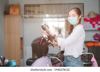 Young Asian Woman Barber Wear Green Surgical Mask, Cut Black Hair Customer. Beautiful Hairstylist Trimming, Dryer In Hair Cut Salon Shop. Female Hairdresser With Face Mask Protect Working In Barber 