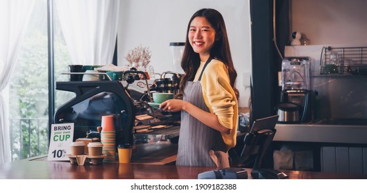 Young Asian woman barista wear apron making coffee cup served to customer at bar counter in coffee shop with smile face.Concept of cafe and coffee shop small business.Vintage tone