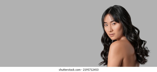 Young Asian Woman With Beautiful Long Wavy Hair On Grey Background With Space For Text