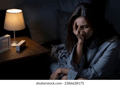 Young Asian woman in bedroom feeling sad tired and worried suffering depression in mental health, woman sitting in bed cannot sleep from insomnia. - Powered by Shutterstock