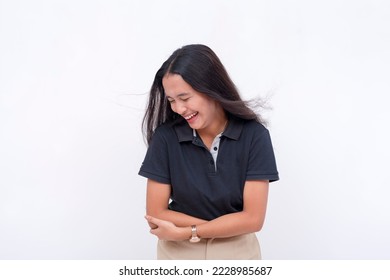 A young asian woman bends down, laughing from a joke. A happy and lighthearted scene. Isolated on a white backdrop. - Shutterstock ID 2228985687