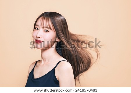Young Asian woman blowing by wind her hair. Beauty, hair care and cosmetics concept.