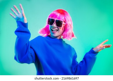 Young asian woman in blue sweatshirt pink short hair punk style wearing sunglasses posing dancing on the green screen background. - Powered by Shutterstock