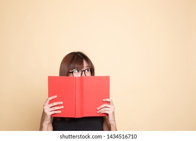 Young Asian Woman With A Book Cover Her Face  On Beige Background