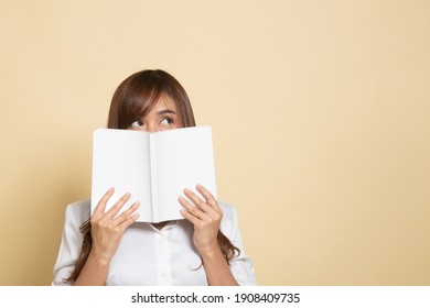 Young Asian Woman With A Book Cover Her Face On Beige Background