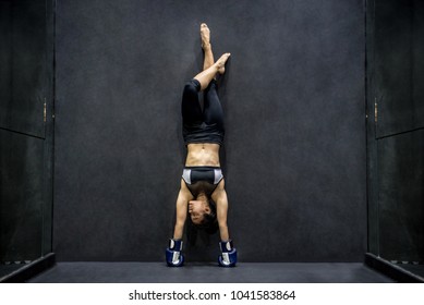 Young Asian woman with boxing gloves doing exercise, handstand posing in fitness gym. healthy lifestyle concept - Powered by Shutterstock