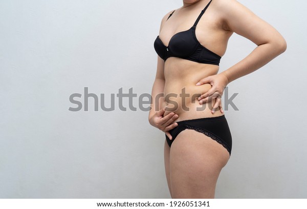 young Asian woman in bra and\
love handles with belly fat. health care, beauty and female\
concept