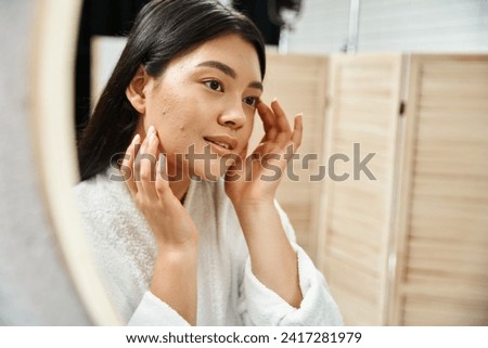 young asian woman with brunette hair examining her skin in the bathroom mirror, skin condition