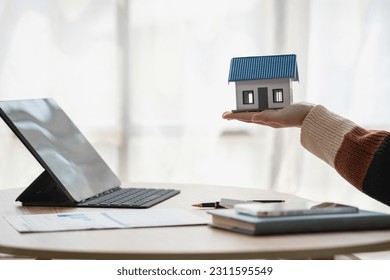 Young Asian woman calculating the cost of selling a house and analyzing the return on real estate investments. Real estate accounting concepts and tax system. - Shutterstock ID 2311595549