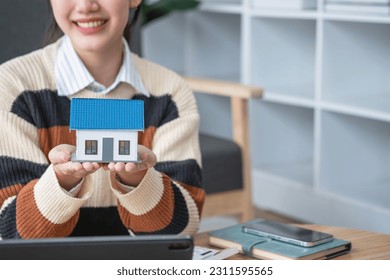 Young Asian woman calculating the cost of selling a house and analyzing the return on real estate investments. Real estate accounting concepts and tax system. - Shutterstock ID 2311595565