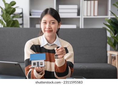 Young Asian woman calculating the cost of selling a house and analyzing the return on real estate investments. Real estate accounting concepts and tax system. - Shutterstock ID 2311595583
