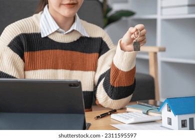 Young Asian woman calculating the cost of selling a house and analyzing the return on real estate investments. Real estate accounting concepts and tax system. - Shutterstock ID 2311595597