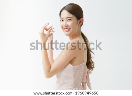 Young Asian woman in the casual dress take off protective facemask after getting Covid-19 vaccinated, concept vaccination campaign. Comfortable breathe while without face mask.Smile with white teeth.