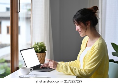 Young Asian Woman In Casual Outfit Sitting At The Desk And Entering Typing Credit Card Number On Laptop, Feeling Excited To Purchase Items From An Online Store, Order Food, Pay Bills.