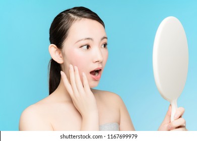 Young Asian Woman Checking Her Face With Hand Mirror.