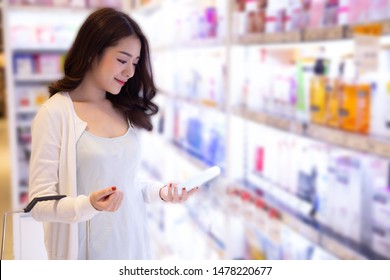 Young Asian Woman Choosing Cosmetic Cream In Beauty Shop