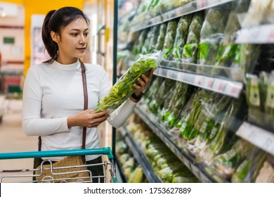 young asian woman choosing vegetables while shopping food in supermarket - Powered by Shutterstock