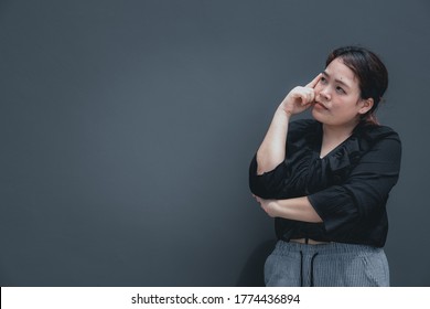 Young Asian Woman With Chubby Body Put Her Finger On Face Looking Away To Think About Something. Copy Space