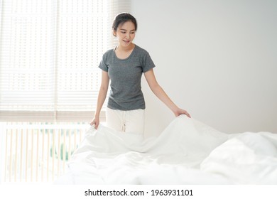 Young Asian Woman Clean Bed. Happy Girl Cleaning The Room Housework And Cleaning Concept.