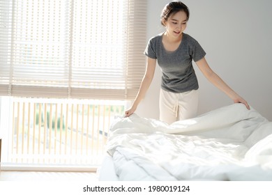 Young Asian Woman Clean Bed. Happy Girl Cleaning The Room Housework And Cleaning Concept.