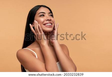 Young Asian woman with clean healthy glowing skin in white top isolated on beige background. Facial skin care concept, spa, cosmetology, plastic surgery. 商業照片 © 