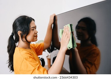 Young Asian woman cleaning tv screen with rag - Shutterstock ID 2366434303