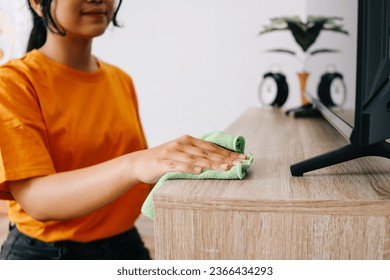 Young Asian woman cleaning and wiping the cabinet tv with microfiber cloth in living room - Shutterstock ID 2366434293