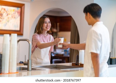 Young Asian woman coffee shop employee barista working at cafe. Smiling female waitress or cashier preparing takeaway order to customer. Small business owner and part time job working concept - Powered by Shutterstock