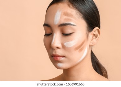 Young Asian woman with contouring makeup on color background