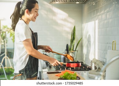 Young Asian Woman Cooking In The Kitchen. Healthy Food - Vegetable Salad. Diet. Healthy Food And Lifestyle. Cooking At Home. Prepare Food.Young Woman Preparing Vegetable Salad In Her Kitchen. 