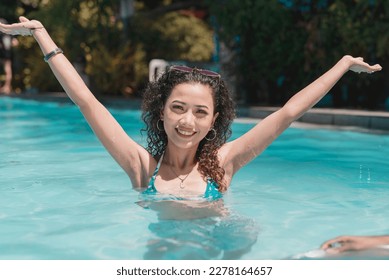 A young asian woman with curly hair relaxing in chest deep waters in the swimming pool. Enjoying her summer vacation. - Powered by Shutterstock