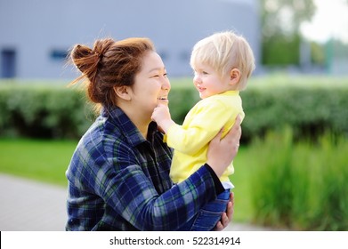 Young asian woman with cute caucasian toddler boy. Babysitting concept