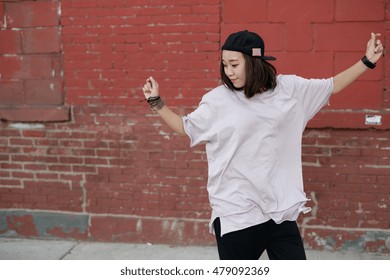 Young Asian Woman Dancing Hip Hop In City Street